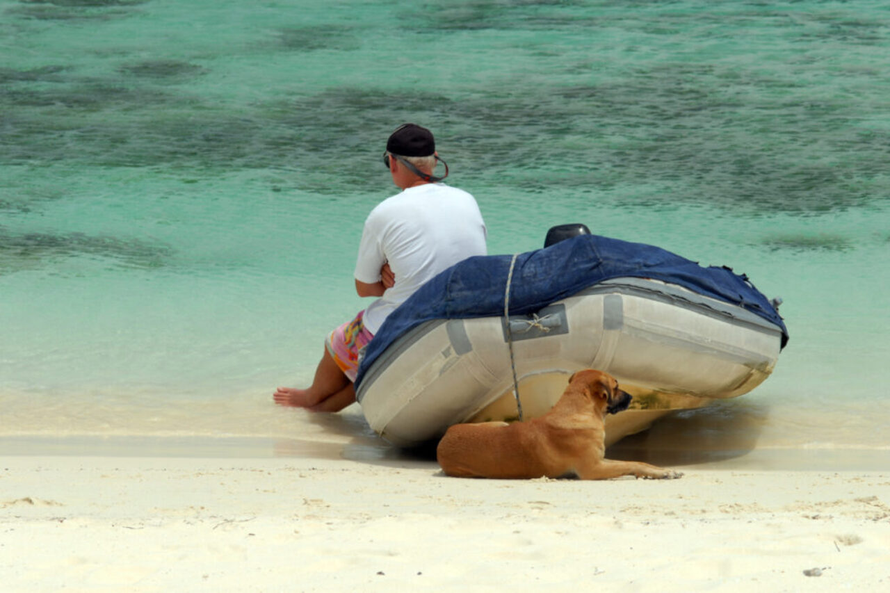 Mann mit Zodiac Boot und Hund am Strand Playa by InsiderFuerteventura