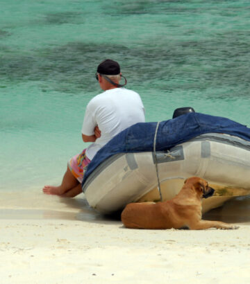 Mann mit Zodiac Boot und Hund am Strand Playa by InsiderFuerteventura